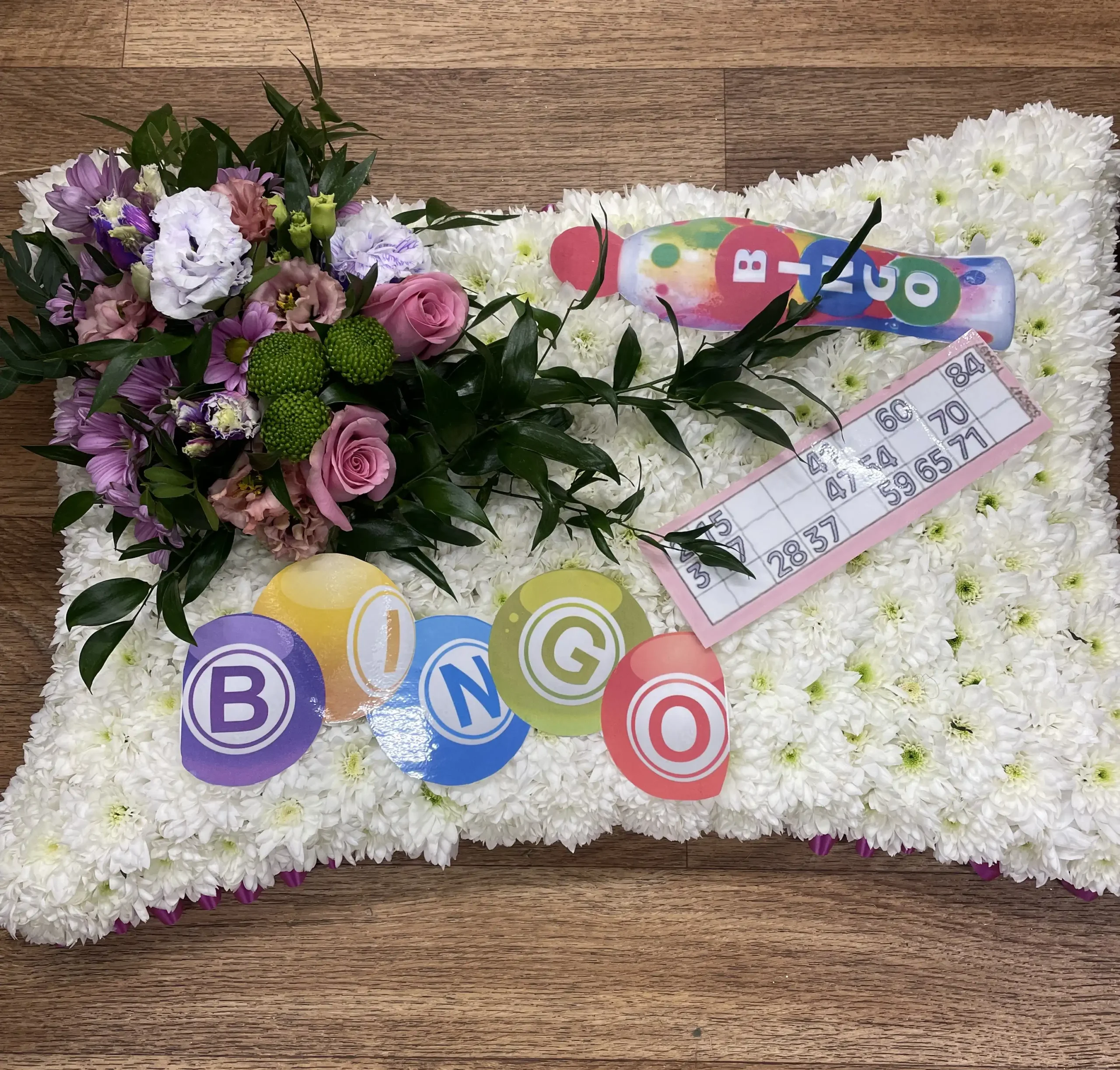 Celebrate cherished memories with our exquisite Bingo Funeral Pillow Tribute from Sun Florist and Events. This personalized tribute adds a heartfelt touch to any memorial service, honoring your loved one's legacy with style and compassion. Explore our beautiful range of funeral florals and custom tributes to ensure a fitting farewell. Contact us today to learn more about our meaningful memorial options.